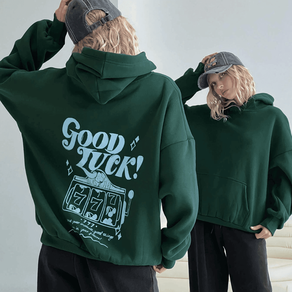 Person in a forest green hoodie with a large printed graphic on the back, next to a friend in a matching hoodie