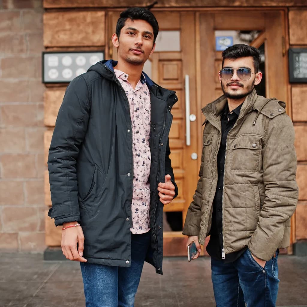 Two men in parka-style jackets standing outside a wooden door