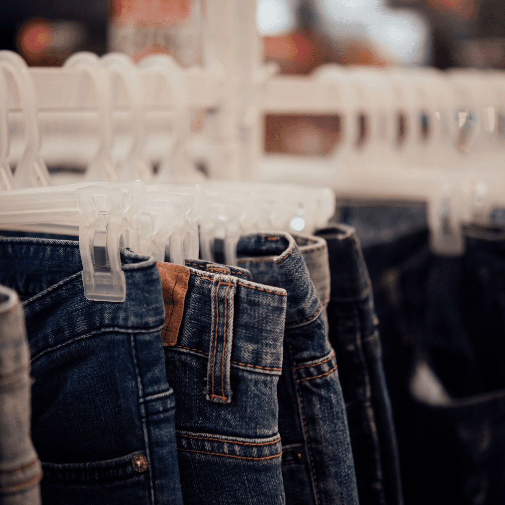 Pairs of jeans in different washes hanging on white hangers on a clothing rail