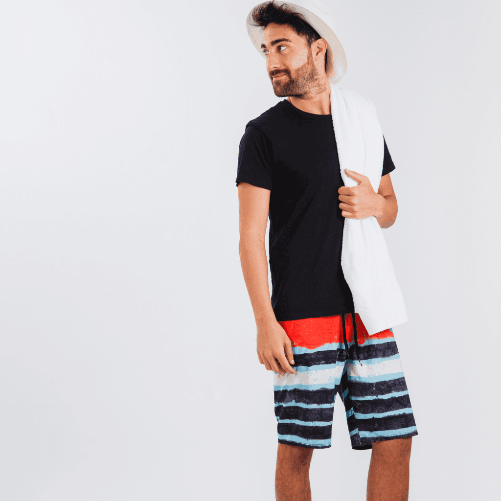 Man in a black t-shirt and red, white and blue striped board shorts holding a white towel