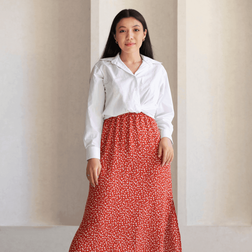 Woman in a white shirt and a red polka-dot midi skirt standing in a bright room