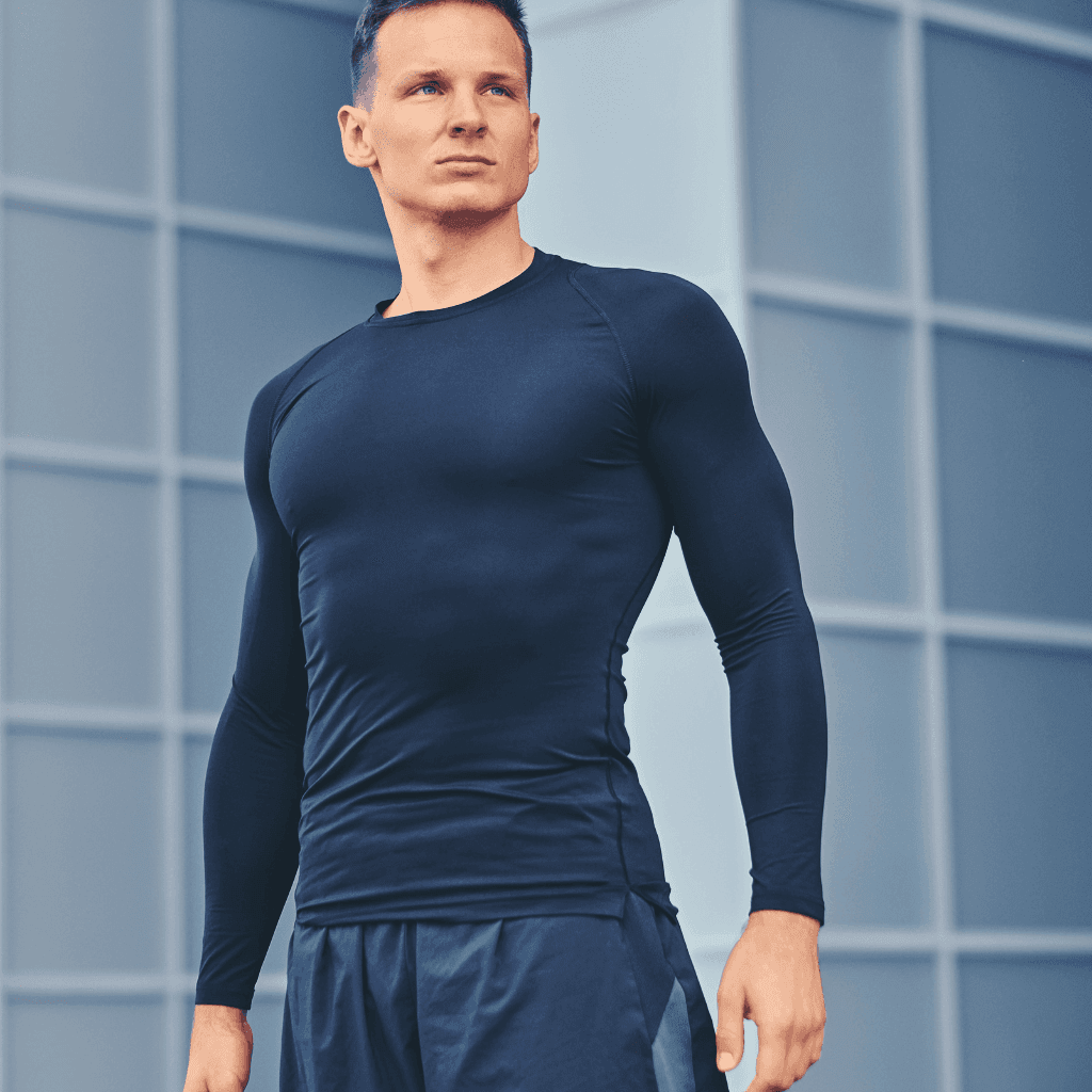 Man in a fitted navy long-sleeve compression top and shorts standing outdoors