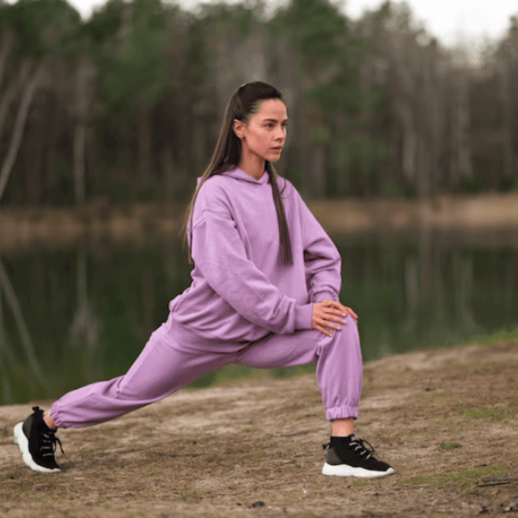 Woman stretching by a lake in a lilac fleece hoodie and matching joggers